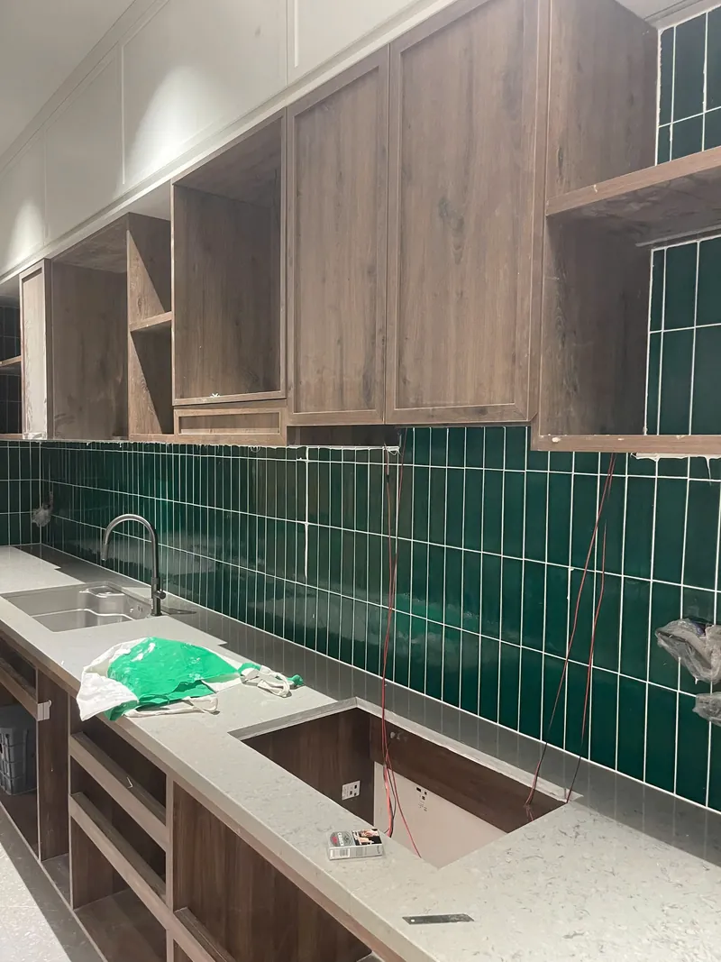Bếp góc rộng với bồn rửa và backsplash gạch thẻ xanh rêu sau khi thi công ron, công trình Bảo Resin tại Đà Nẵng