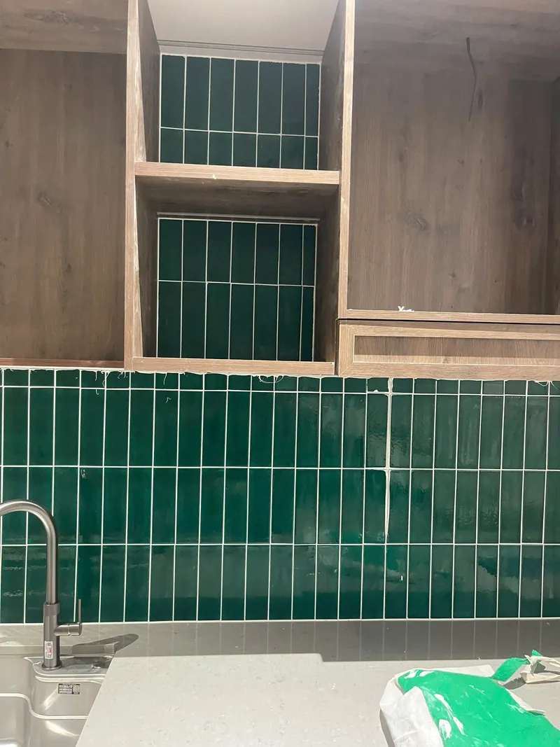 Bếp tủ gỗ với backsplash gạch thẻ xanh rêu và đường ron trắng đều, công trình Bảo Resin tại Đà Nẵng