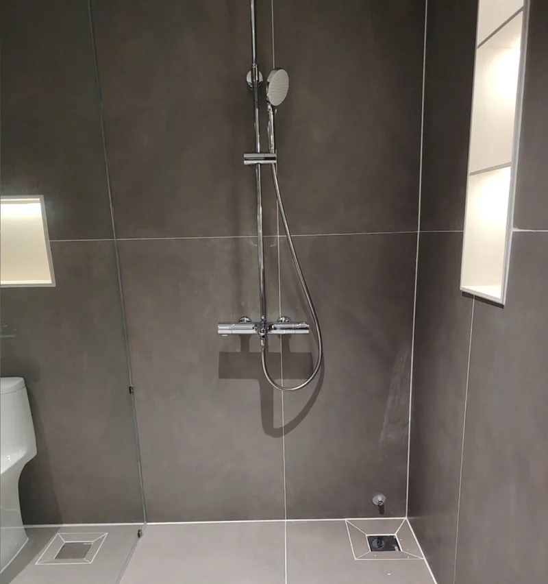 Khu tắm đứng ốp gạch xám khổ lớn với đường ron sáng đều sau khi thi công ron epoxy, công trình Bảo Resin tại Đà Nẵng