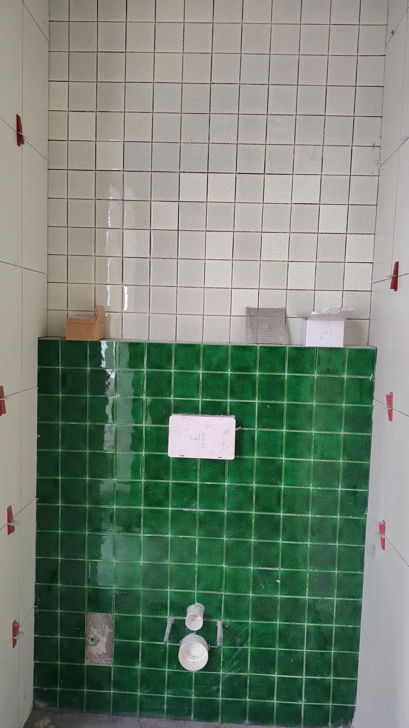 Mảng tường gạch xanh lá quanh khu bồn cầu treo với đường ron epoxy trắng đều, công trình Bảo Resin tại Đà Nẵng